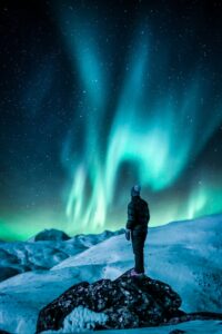 man standing on a rock near snow covered land